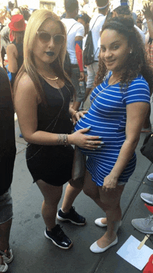 a pregnant woman in a blue striped dress is standing next to another woman
