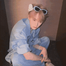 a man wearing sunglasses and a flower in his hair looks at the camera