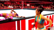 two women are wrestling in a ring and one is laying on the ground .
