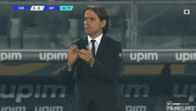 a man in a suit and tie applauds in front of an upim sign