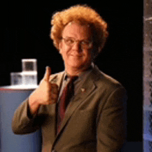 a man wearing a suit and tie is giving a thumbs up