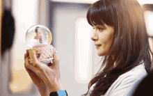 a woman holding a snow globe with a ballerina inside