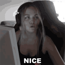 a woman wearing headphones is sitting in front of a computer screen with the words nice written on it