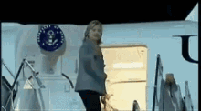 a woman is standing in front of a white airplane with the letter u on it