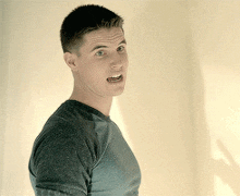 a man in a grey shirt is making a face