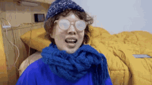 a person wearing glasses and a scarf is making a face