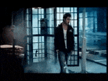 a man in a black jacket is walking through a doorway .