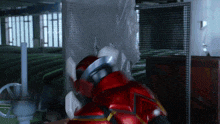 a man in a red suit is standing in a room with a fence