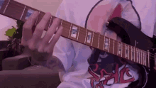 a person is playing an electric guitar while wearing a t-shirt that says ' slayer ' on it .