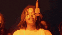 a woman with dreadlocks is singing into a microphone in front of a crowd .