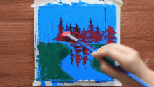 a person is painting a picture of a river with trees