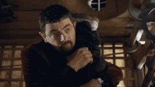 a man with a beard is holding a ring in his left hand