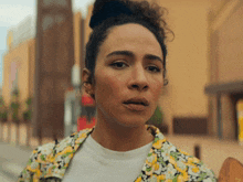 a woman with curly hair is wearing a floral jacket and a white shirt