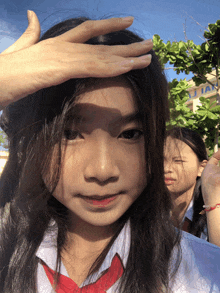 a girl covering her face with her hand with a building in the background that says tai