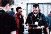 a group of doctors are looking at a tablet and one of them has a name tag with the number 3 on it