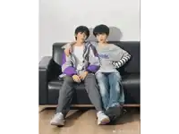 two young men are sitting on a couch with one wearing a shirt that says " seoul "