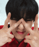 a close up of a person making a face with their fingers on their nose