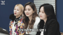 three women are sitting next to each other with twice written on the bottom right