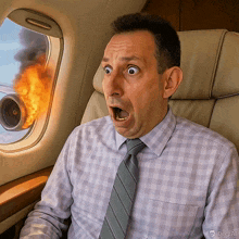 a man in a plaid shirt and tie is looking out the window of an airplane with flames coming out of it