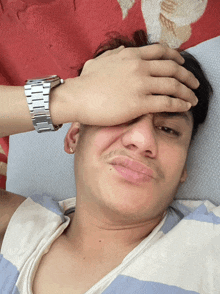 a man with a watch on his wrist is covering his face