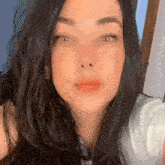 a close up of a woman 's face with long black hair and a nose piercing .
