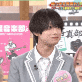 a man in a suit and tie stands in front of a pink sign that says ' a ' on it