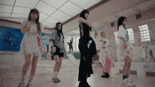 a group of girls are dancing in a room with a painting on the wall