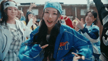 a girl wearing a blue jacket with the letter t on the front