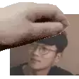 a hand is holding a piece of cardboard over a man 's face .