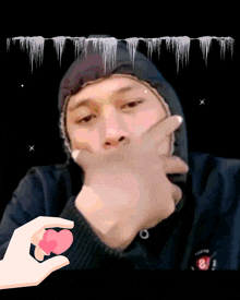a person holding a heart in front of a man with a hoodie on