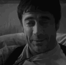 a man in a suit and tie is laying on a bed and smiling .