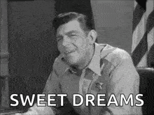 a man in a sheriff 's uniform is sitting at a desk and says sweet dreams .