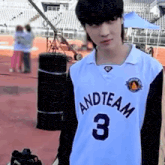 a young man wearing a white and team 3 basketball jersey is standing on a field .