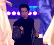 a man singing into a microphone with a purple background