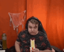 a man wearing headphones is eating a sandwich in front of an orange curtain