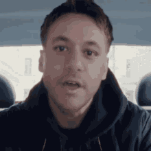a man wearing a black hoodie looks at the camera