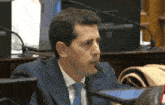 a man in a suit and tie is sitting in front of a microphone