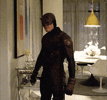 a man in a daredevil costume stands in a dining room