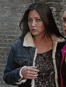 a woman is wearing a denim jacket with a fur collar .