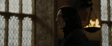 a man in a black coat stands in front of a window