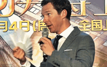 a man in a suit holds a microphone in front of a sign that says ' mollyhobbie ' on it