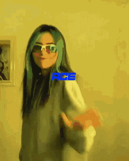 a girl with blue hair is wearing sunglasses and a white shirt with the ace logo on it