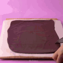 a person is cutting a piece of chocolate with a knife on a cutting board