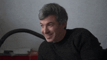 a man in a black sweater is smiling and looking to the side