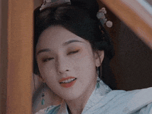 a close up of a woman 's face with her eyes closed and a flower in her hair
