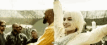 a woman in a white dress is dancing with a man in a yellow jacket .