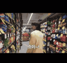 a woman is walking down a grocery store aisle with chinese writing on the bottom right