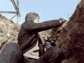 a man in a trench holding a gun in his hand