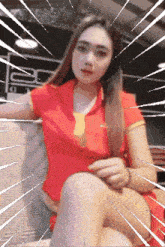 a woman in a red shirt and tie is sitting on a chair