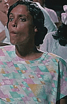 a woman wearing a multicolored shirt is standing in a crowd of people .